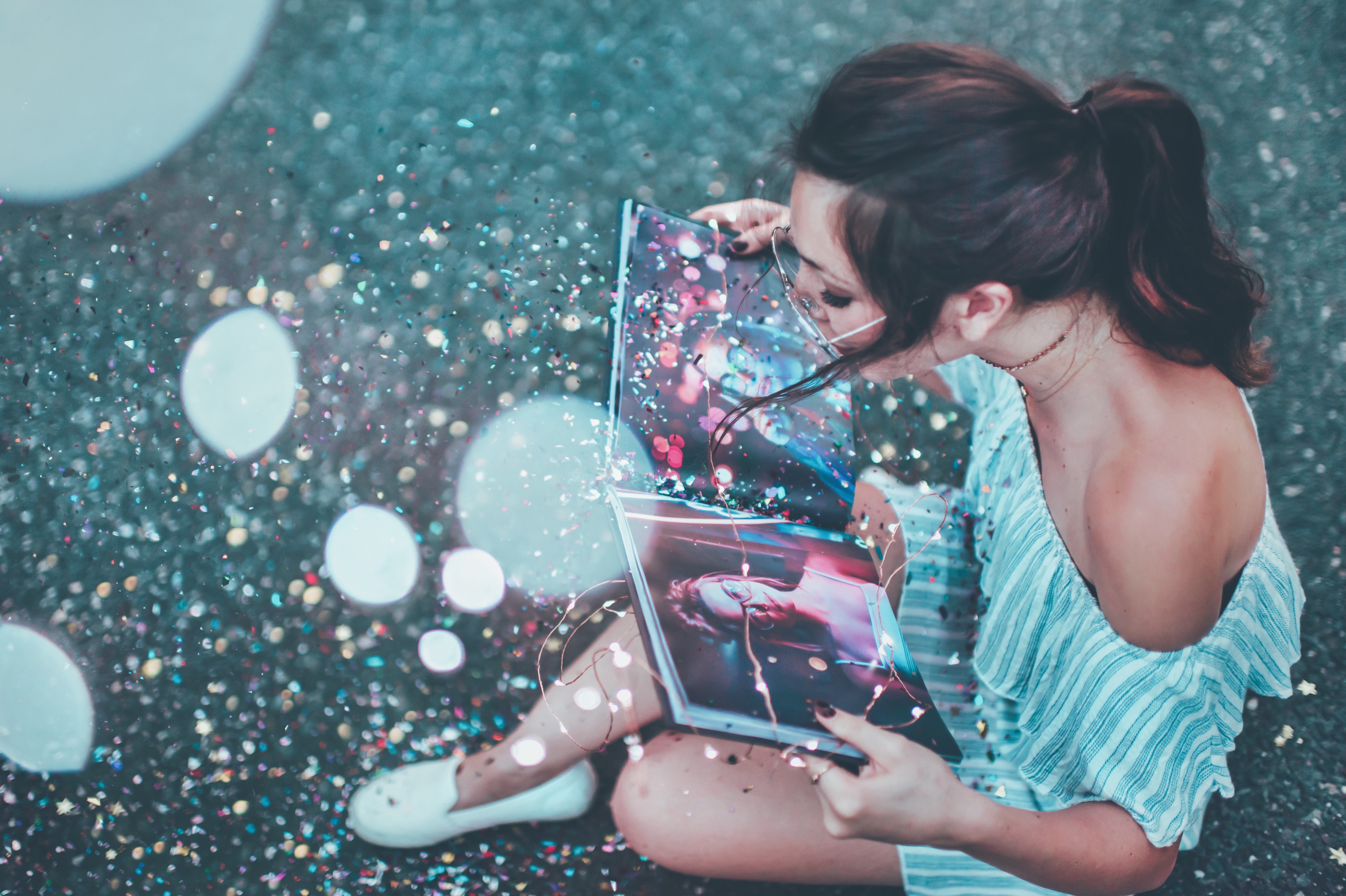 girl sitting in the street, reading a book surrounded by glitter